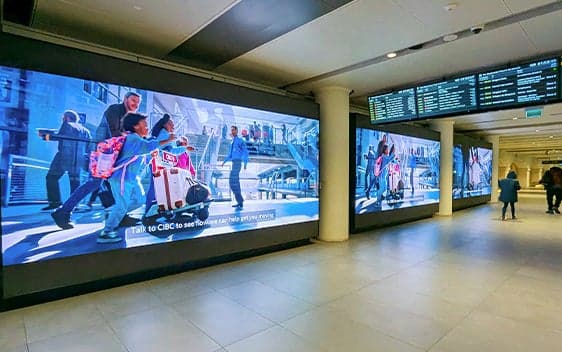 Terminal corridor with large digital display screens and overhead information boards.