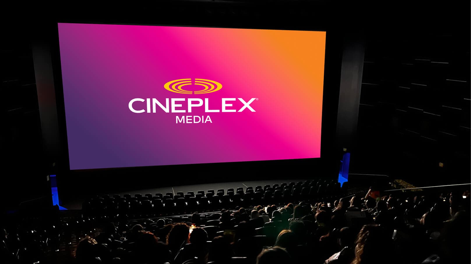 Cinema audience seated in a theatre watching a Cineplex Media branding screen with gradient background