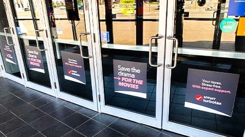 Cineplex entrance doors with Intuit TurboTax ads featuring the message “Save the drama for the movies”