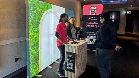 TurboTax representative standing at branded concierge booth with welcome signage