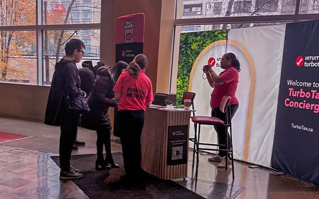 People interacting at an Intuit TurboTax promotional concierge booth in a mall