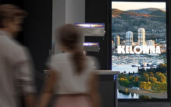 Digital lobby screen displaying Kelowna cityscape inside a Cineplex theatre