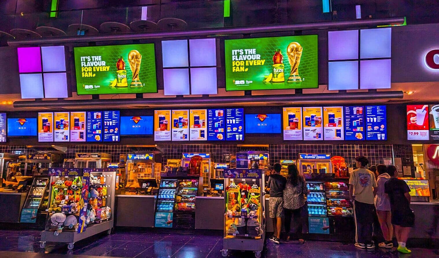 Digital screens at Cineplex Cinemas Markham displaying Fuze beverage ad above concession stand