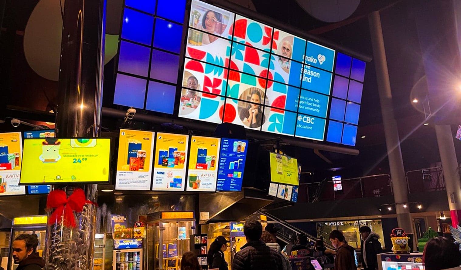 Écrans numériques au Cineplex Cinemas Mississauga Square One affichant une publicité pour la boisson Fuze au-dessus du comptoir de concessions