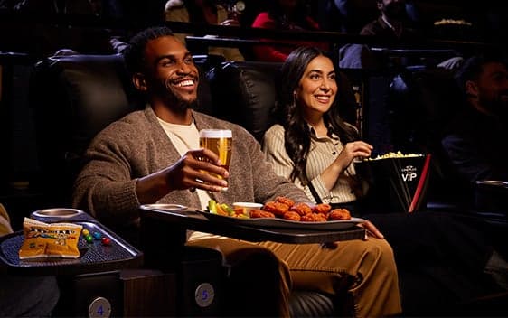 Guests enjoying Cineplex VIP experience with gourmet food and drinks in recliner seats
