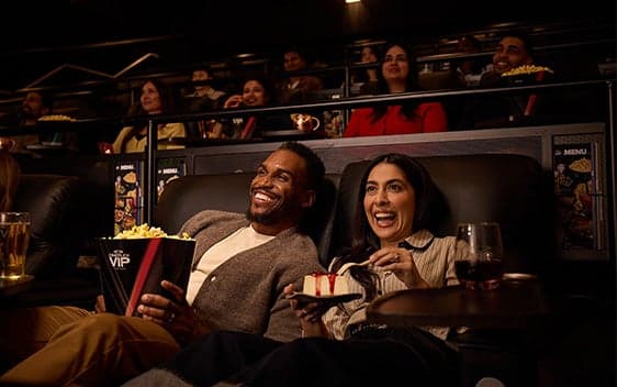 Invités profitant de l’expérience VIP de Cineplex avec mets gourmets et boissons dans des fauteuils inclinables