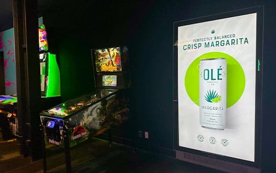 Digital portrait screen in an arcade displaying an ad for Olé crisp margarita beverage
