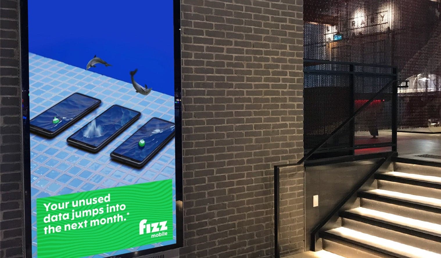 Digital screen at The Rec Room displaying Fizz Mobile ad about rolling over unused data
