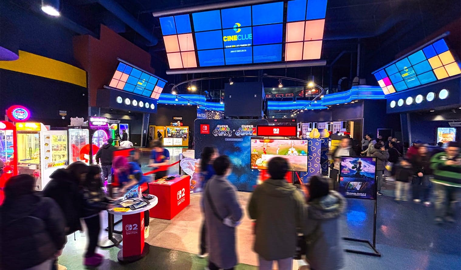 Guests exploring Nintendo-themed gaming area with large branded screens and consoles