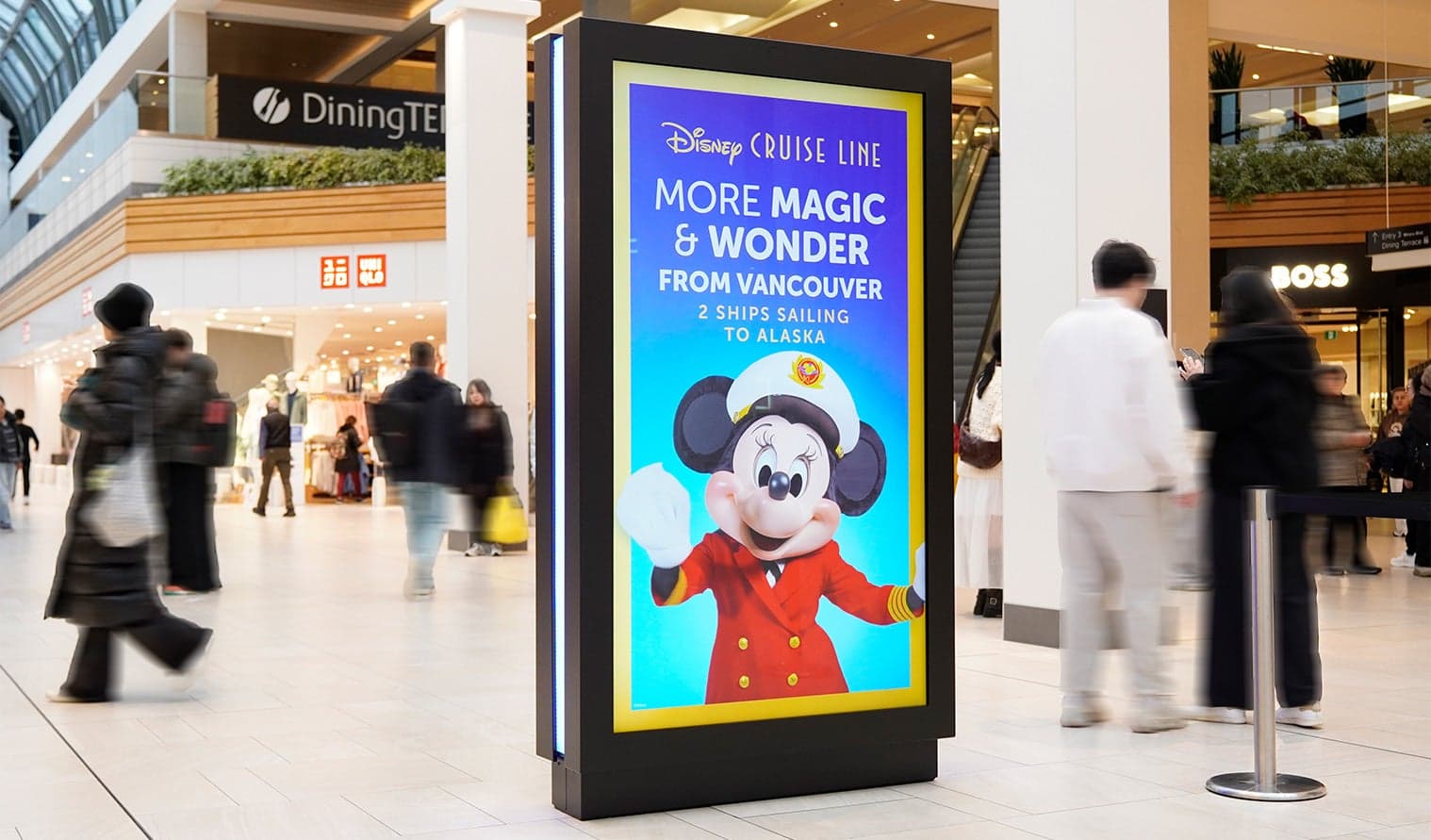 Shoppers passing a digital ad for Disney Cruise Line featuring Mickey Mouse at CF Richmond Centre